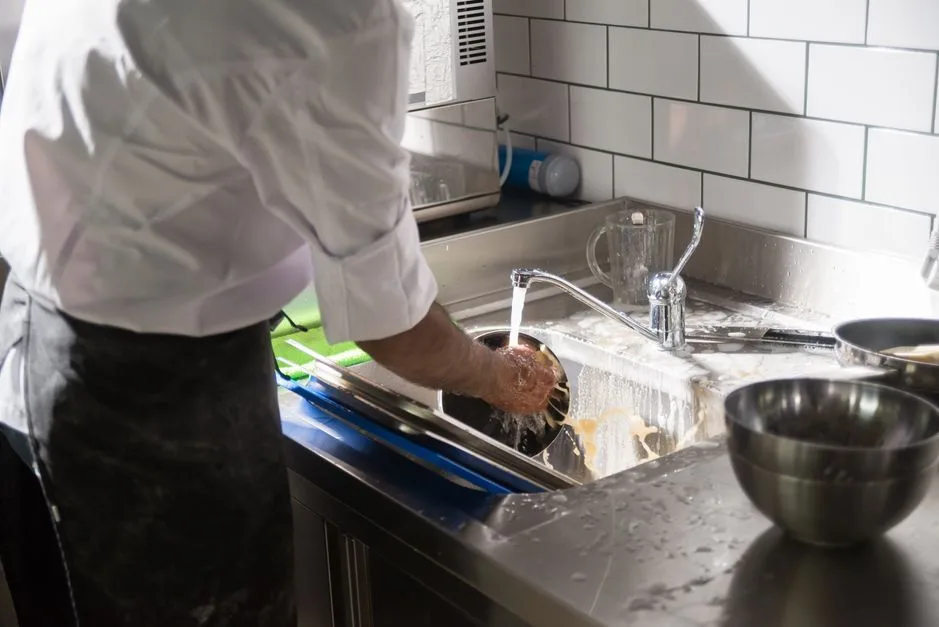 Commercial kitchen worker maintaining hood filter equipment