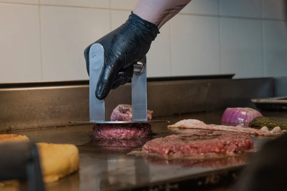 Chef cooking over commercial grill generating grease that flows to trap below